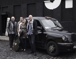 Members of VIDA Guitar Quartet pose in front of a taxi.